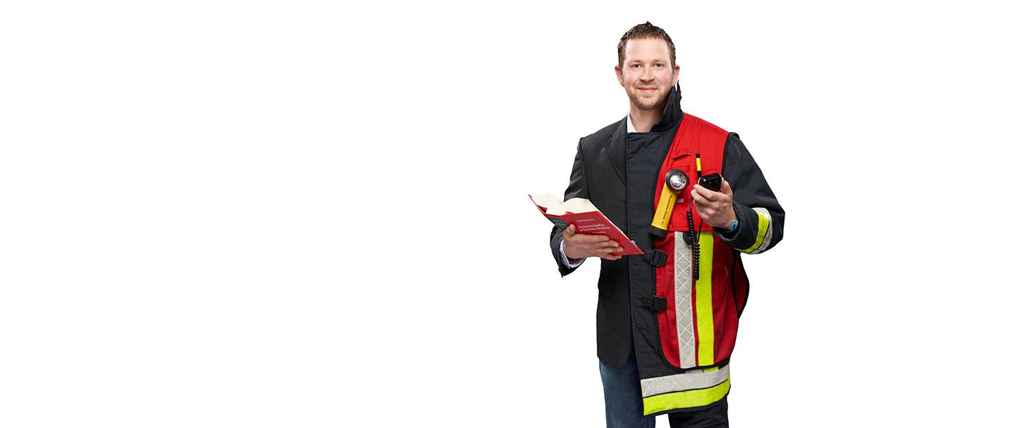 Fotomontage eines Mannes: Halb Verwaltungswirt in dunklem Sakko und Jeans, halb Feuerwehrmann in Uniform. Er trägt ein Funkgerät, eine rote Gruppenführerweste und ein Buch mit Gesetzestexten.