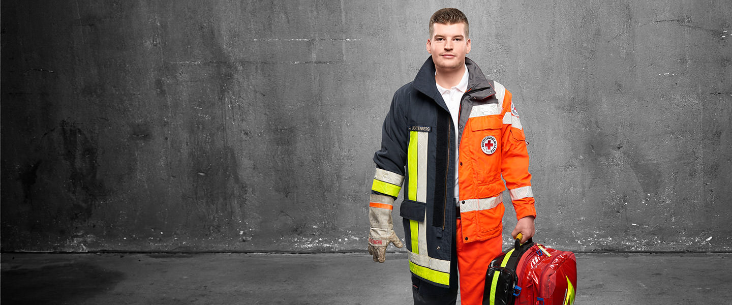 Fotomontage eines Mannes: Halb Rettungsassistent in Arbeitskleidung, halb Feuerwehrmann in Uniform. Er trägt einen Rettungsrucksack.