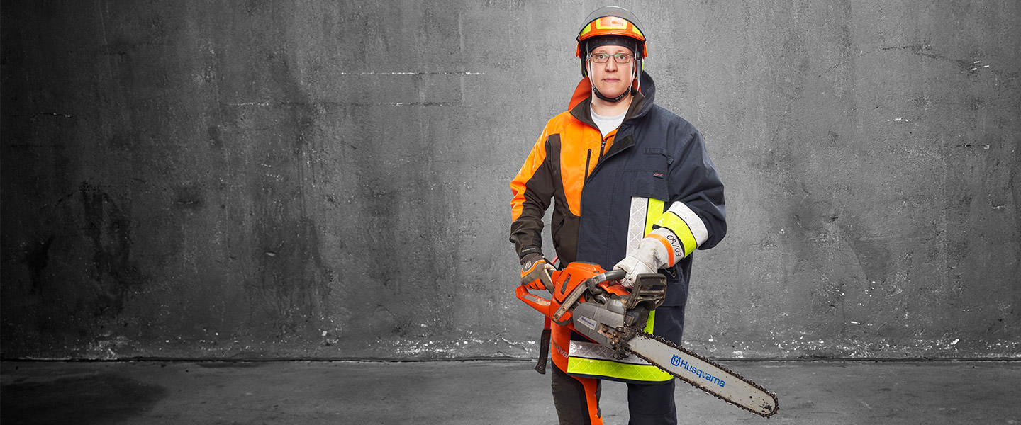 Fotomontage eines Mannes: Er trägt zur Hälfte orange-schwarze Schutzkleidung für Arbeiten mit der Kettensäge, zur anderen Hälfte ist er Feuerwehrmann in Uniform. Er hält mit beiden Händen eine Kettensäge.