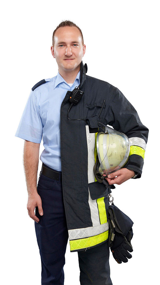 Fotomontage eines Mannes: Zur einen Hälfte Justizvollzugsbeamter, zur anderen Feuerwehrmann. Unter seinem linken Arm trägt er einen Feuerwehrhelm.
