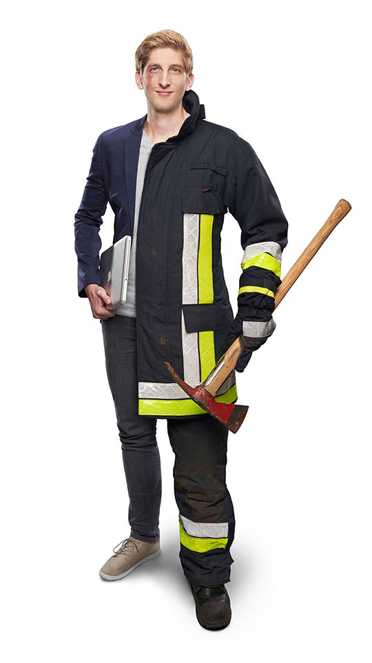 Fotomontage eines Mannes: Halb als Doktorand in Jeans und blauem Sakko, halb Feuerwehrmann in Uniform. Er trägt einen Laptop und eine Feuerwehraxt in den Händen.