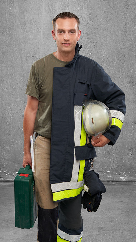 Fotomontage eines Mannes: Halb Tischlermeister in heller Arbeitshose und hellem T-Shirt, halb Feuerwehrmann in Uniform.